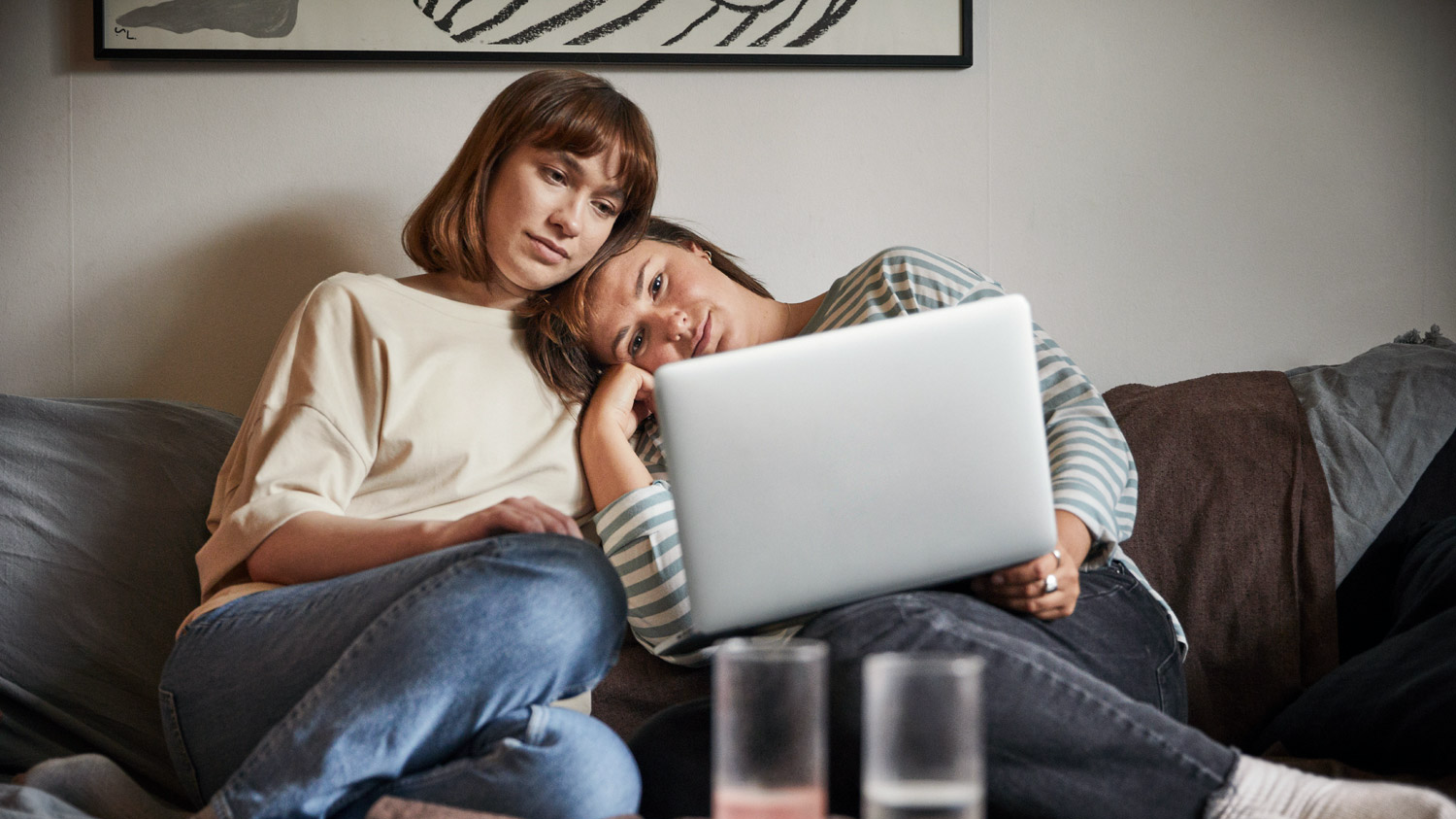 An image of two female friends in the sofa looking at a laptop